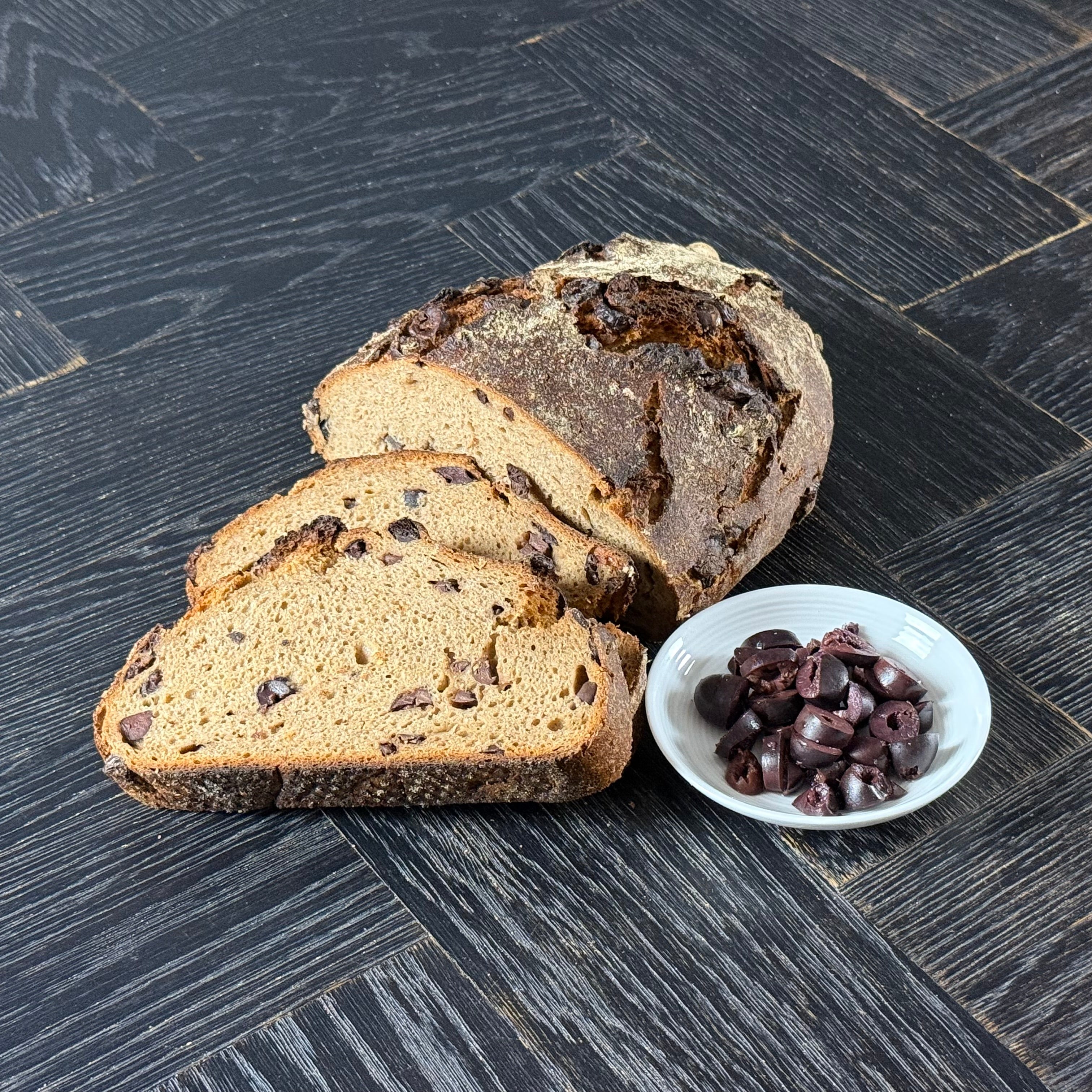Aufgeschnittenes Gaues Oxbrot mit luftiger Krume und sichtbaren Kalamata Oliven im Teig